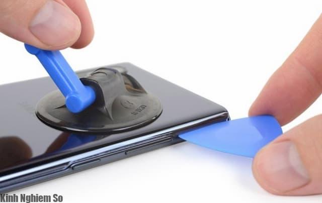 Các kỹ thuật viên sử dụng khò nóng và các dụng cũ hỗ trợ để hút và lẫy mặt lưng của máy